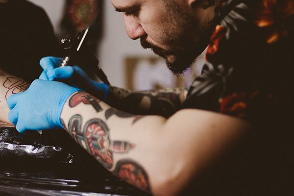 Татуировщик работает с высокой концентрацией внимания